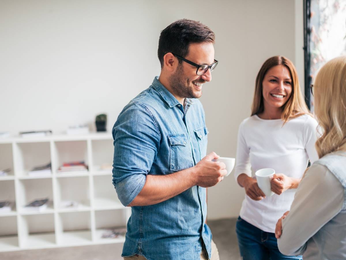 Trzy osoby piją kawę i rozmawiają.