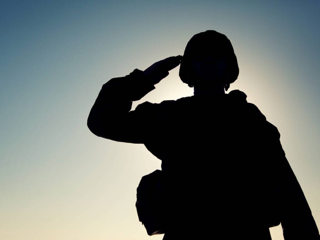 Salutujący żołnierz na tle nieba.