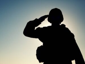 Salutujący żołnierz na tle nieba.