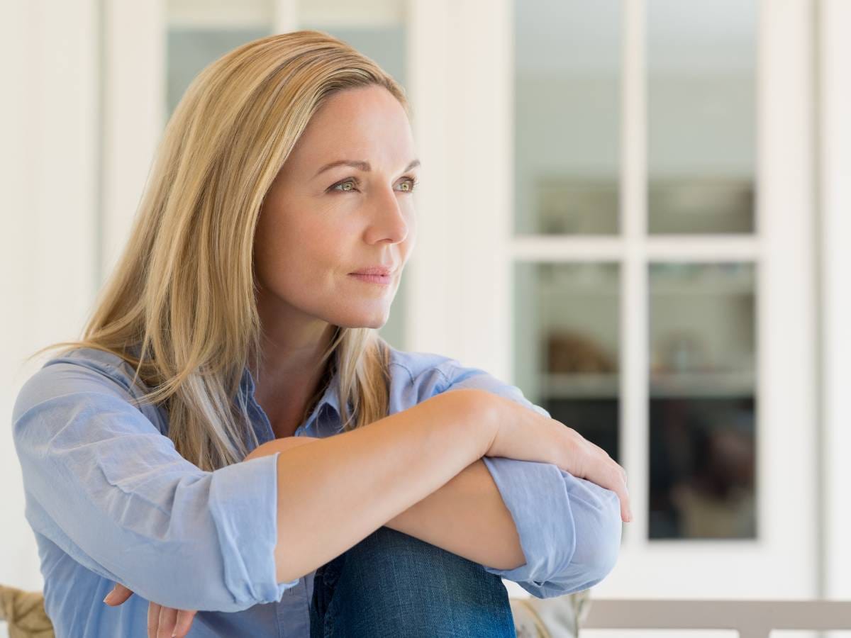 Zamyślona kobieta na tle okna.