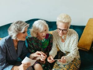 Trzy panie na kanapie w trakcie oglądania zdjęć i rozmowy.