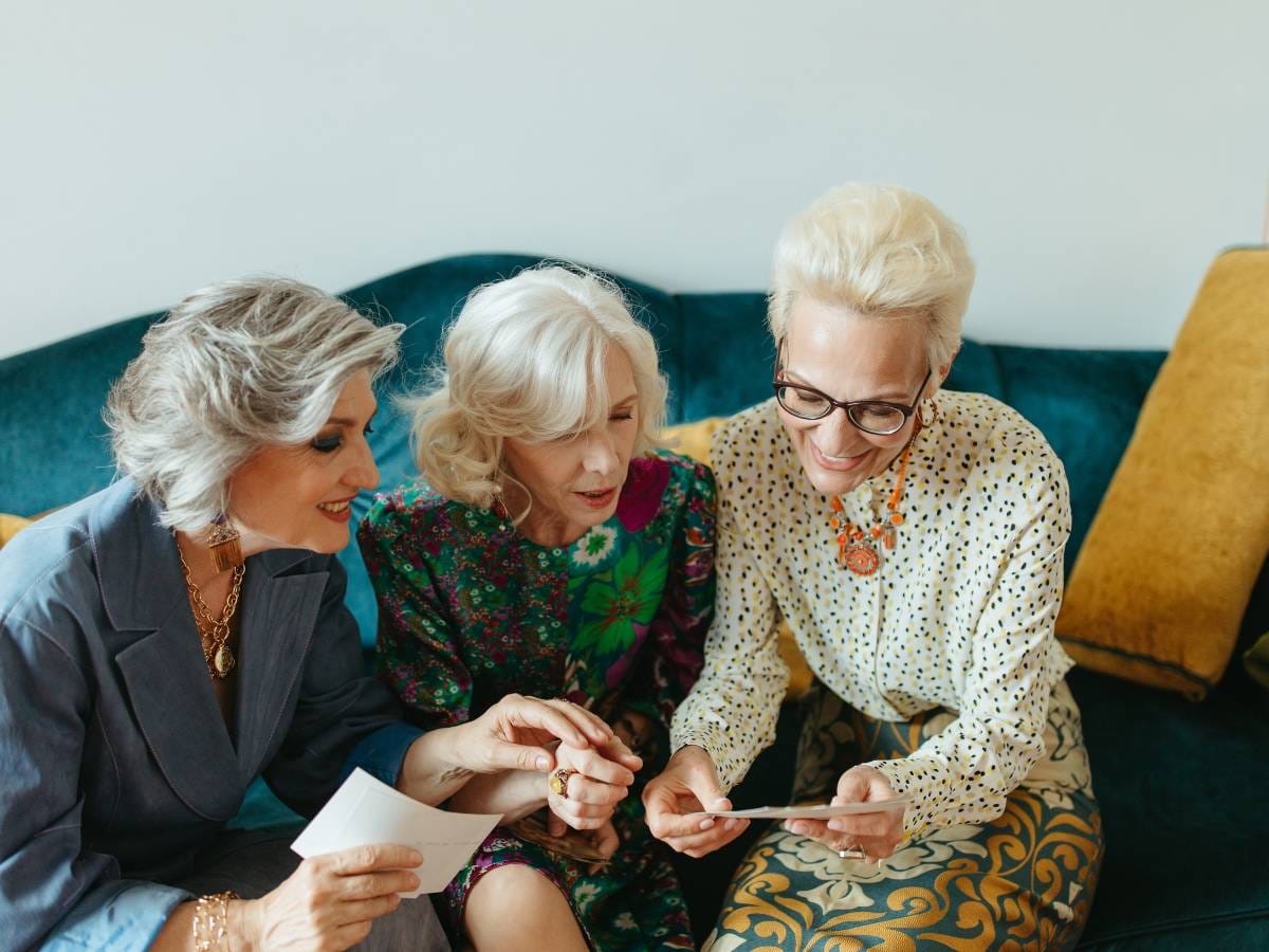 Trzy panie na kanapie w trakcie oglądania zdjęć i rozmowy.