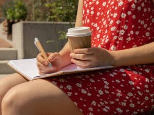 Dziewczyna w czerwonej sukience pisze w notatniku