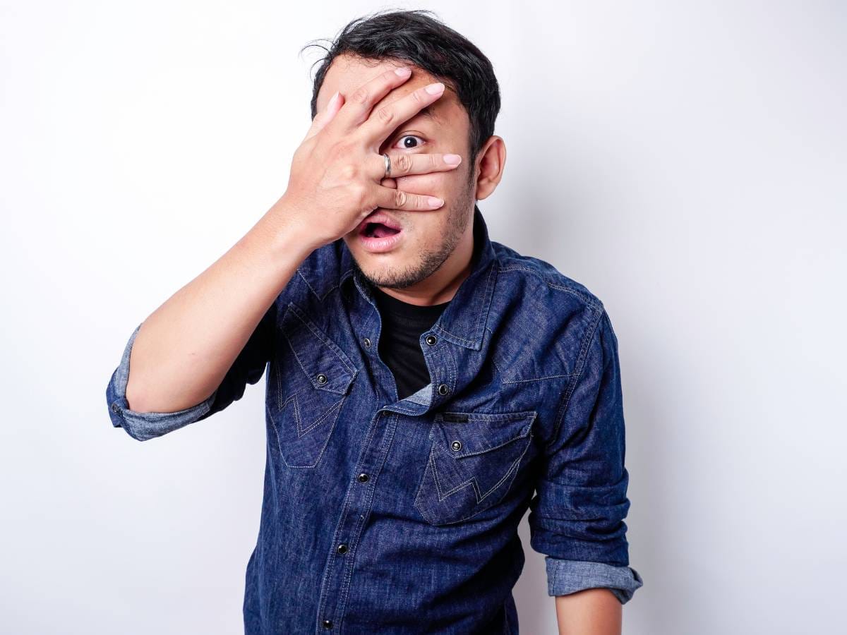 Mężczyzna patrzący przez palce.