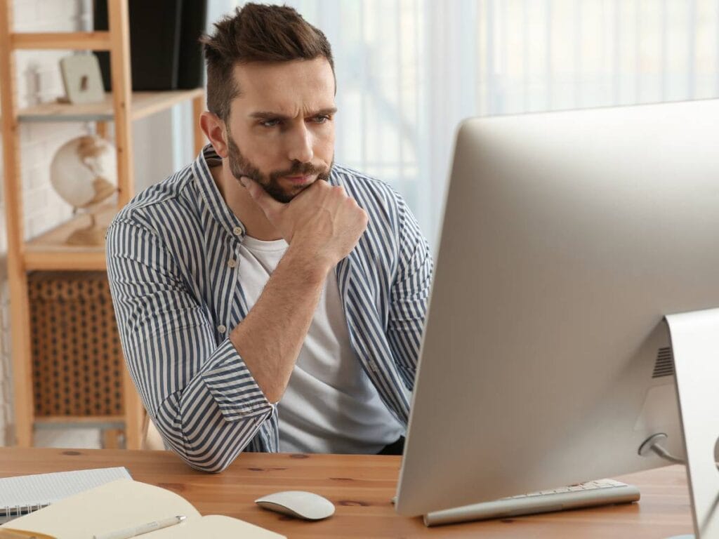 Zamyślony mężczyzna przed laptopem.