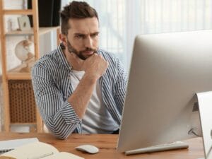 Zamyślony mężczyzna przed laptopem.