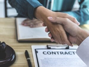 Widok uścisku dłoni ponad stołem z dokumentami.