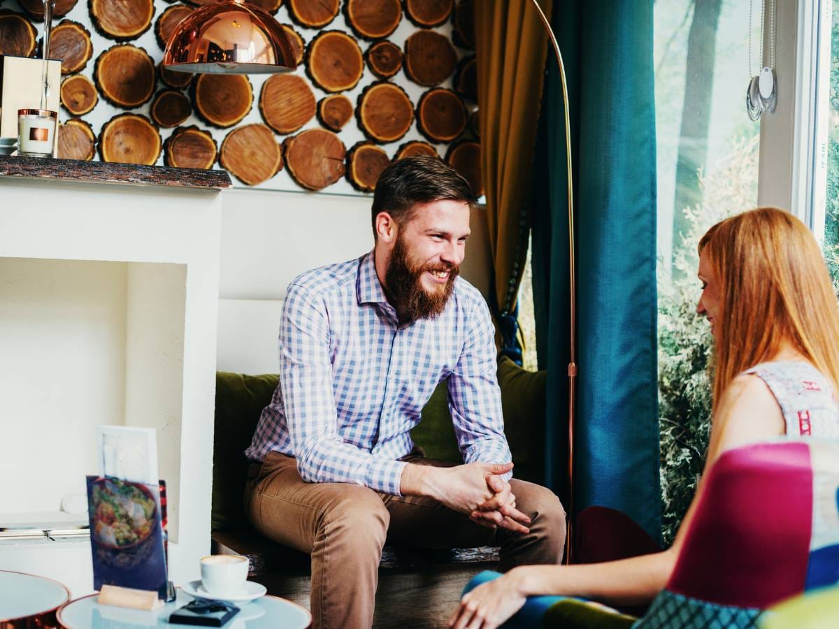 Dwoje ludzi siedzi na przeciw siebie i rozmawia.