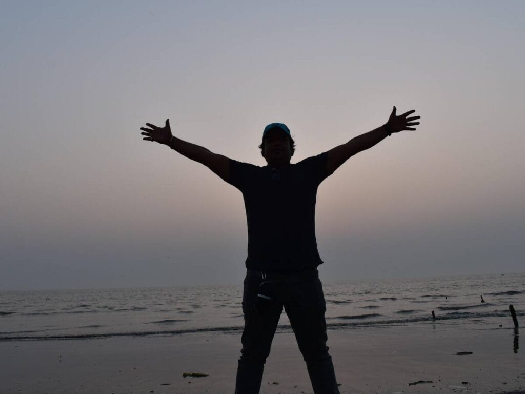 Mężczyzna na tle wody, w geście zwycięstwa.