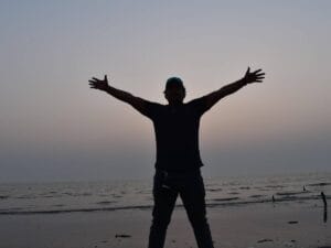 Mężczyzna na tle wody, w geście zwycięstwa.