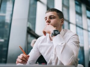 Mężczyzna w białej koszuli przy pracy przed laptopem