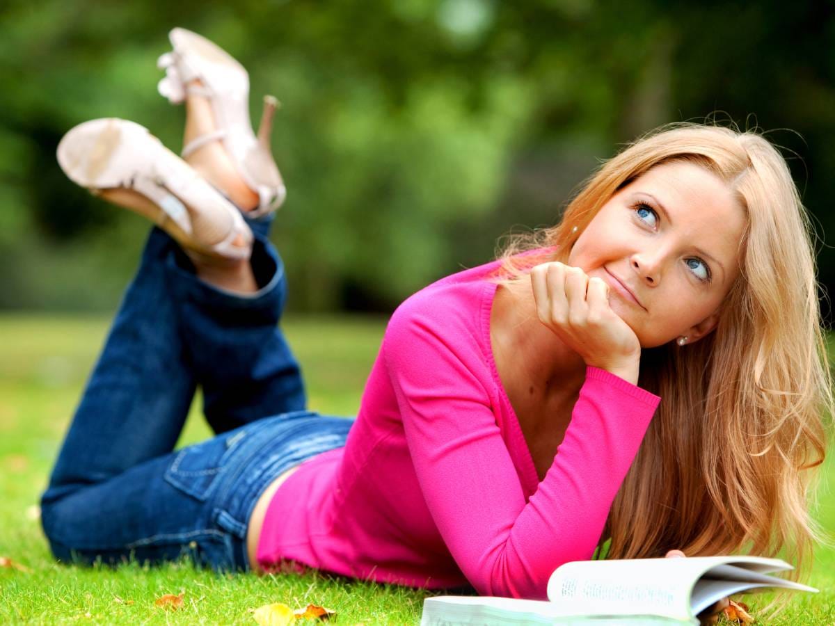 Kobieta leżąca na trawie z książką
