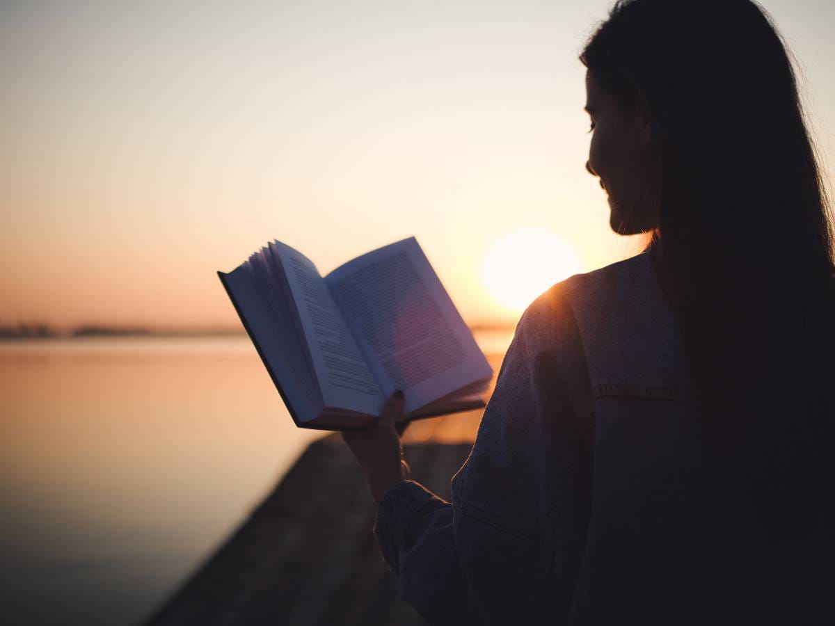 Kobieta z książką i zachód słońca