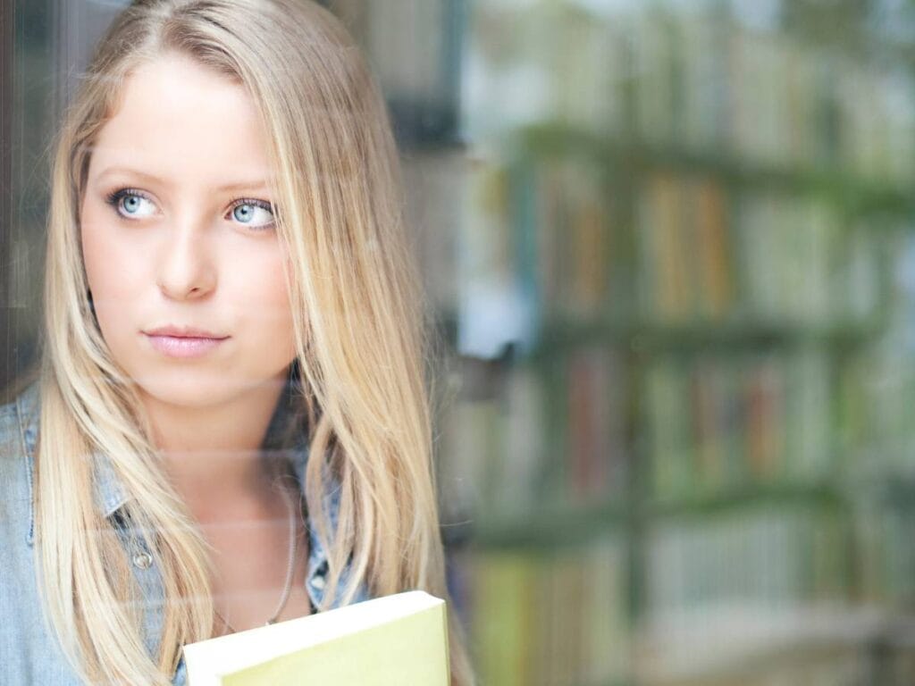 Zamyślona kobita na tle książek