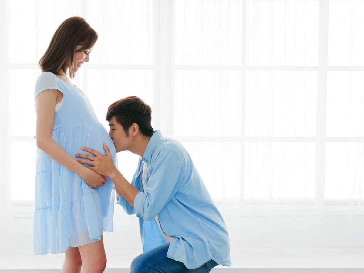 Kobieta w ciąży i mężczyzna całujący brzuszek