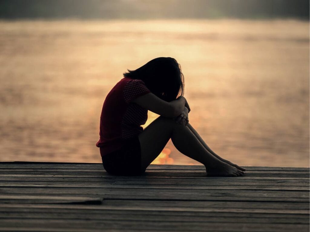 Smutna kobieta na tle zachodzącego słońca