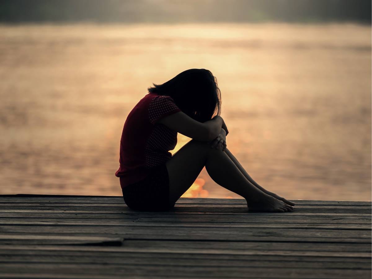 Smutna kobieta na tle zachodzącego słońca