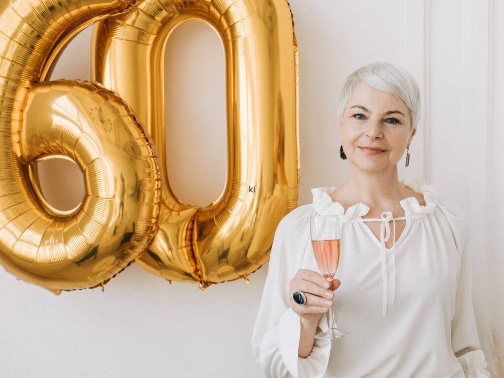 Liczba 60 ze złotych balonówy kobieta z kieliszkiem szampana